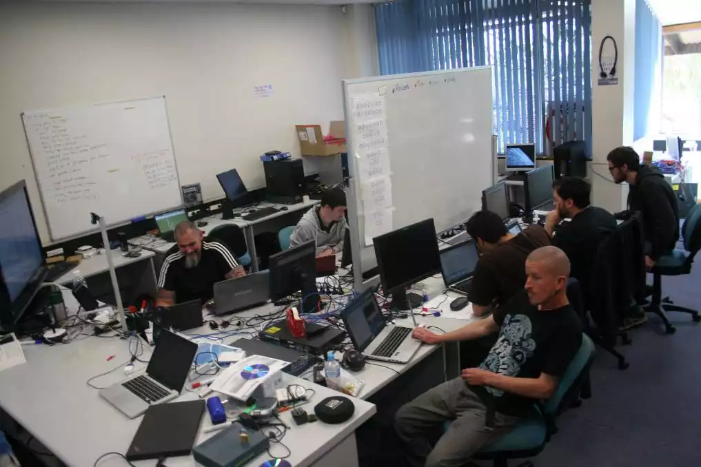 A busy computer network with whiteboards. Multiple laptops on a table.